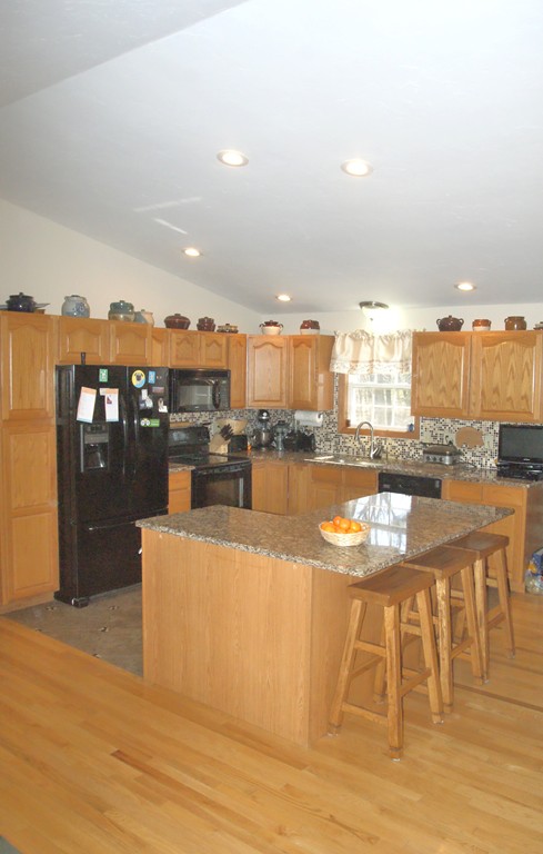 82 Baker Pond Road Dudley, MA 01571 - Photo 7 of 29 a kitchen with stainless steel appliances kitchen island granite countertop a table and chairs in it
