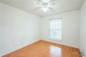 an empty room with windows and ceiling fan