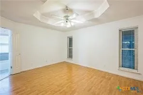 an empty room with a chandelier fan and windows