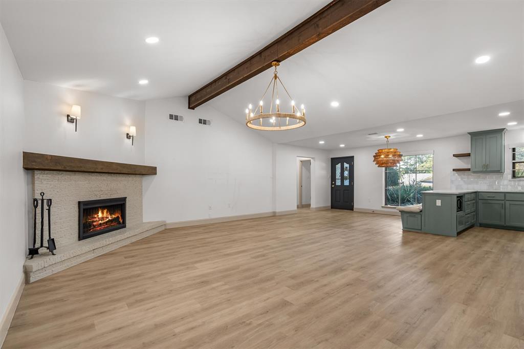 2108 Forest Hills Road Grapevine, TX 76051 - Photo 15 of 40 Vaulted ceiling with exposed wood beam, wood-finish flooring, brick fireplace with wood mantel, recessed lighting, and a modern chandelier