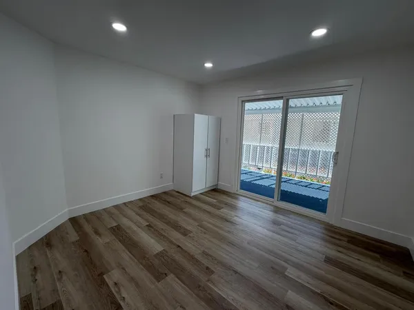 a view of an empty room with wooden floor and a window