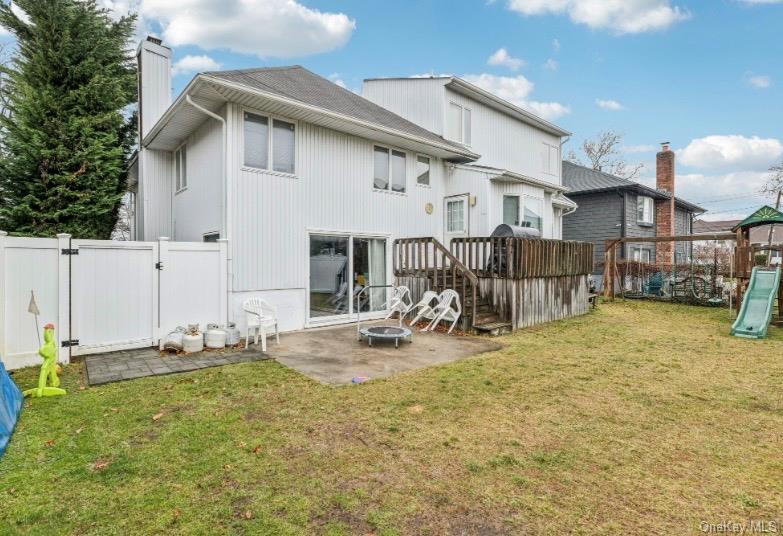 575 Rica Lane Woodmere, NY 11598 - Photo 20 of 24 Rear view of property with a gate, a fenced backyard, a patio area, a chimney, and a playground