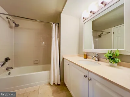 a bathroom with a granite countertop sink a mirror a bathtub and shower
