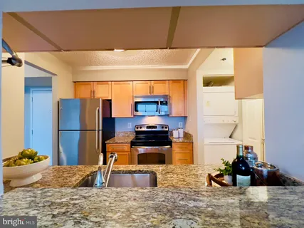 a kitchen with stainless steel appliances kitchen island granite countertop a refrigerator and a sink