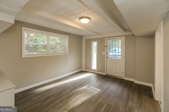 a view of an empty room with wooden floor and a window
