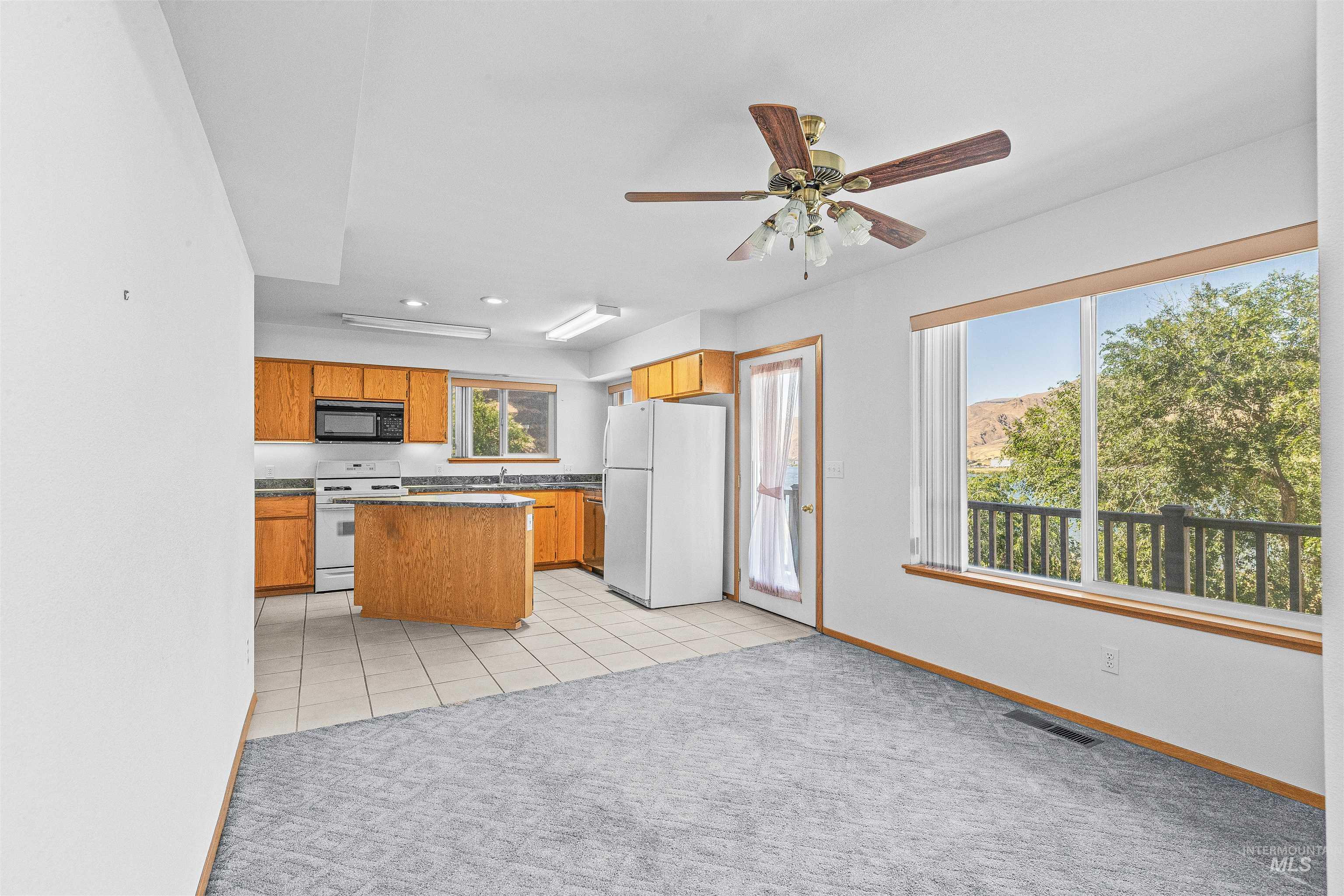 1962 Golfview Drive Clarkston, WA 99403 - Photo 19 of 35 Kitchen featuring white appliances, light carpet, brown cabinetry, dark countertops, and ceiling fan