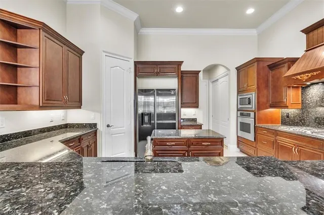 a kitchen with stainless steel appliances granite countertop a refrigerator and a stove top oven