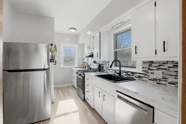 a kitchen with a refrigerator sink and white cabinets