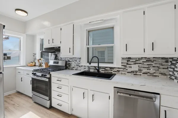 a kitchen with white cabinets and appliances