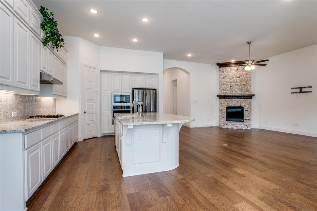 717 Corner Post Path Celina, TX 75009 - Photo 4 of 12 a large kitchen with cabinets wooden floor and stainless steel appliances