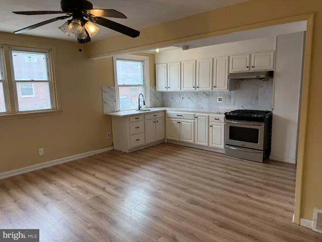 a kitchen with stainless steel appliances granite countertop a stove a sink and white cabinets with wooden floor