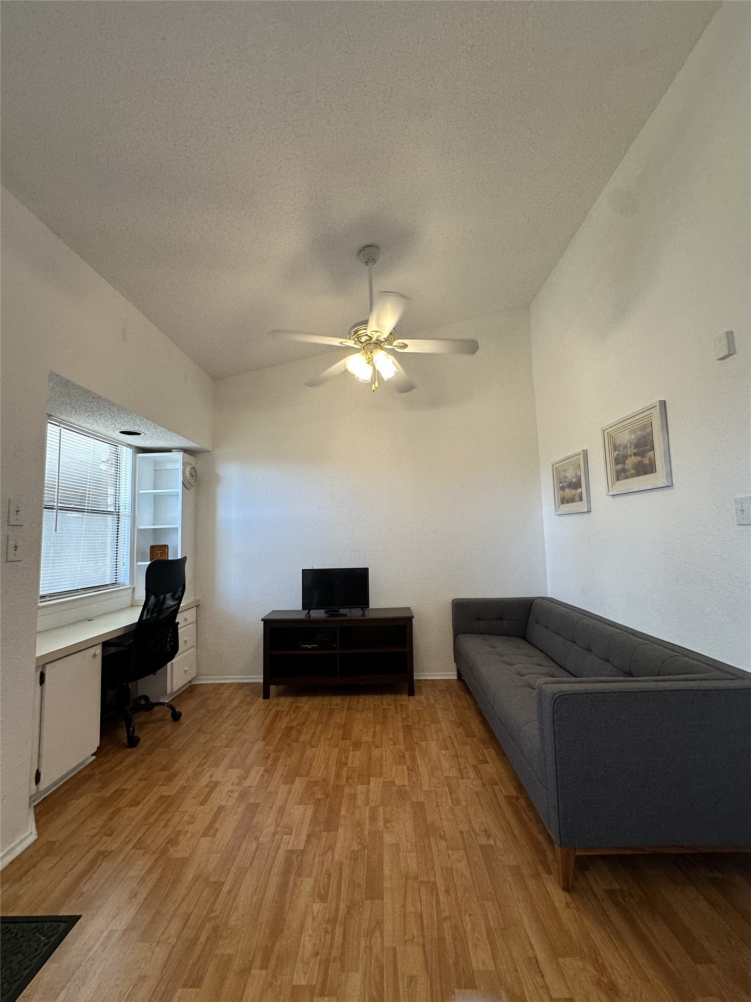 3316 Guadalupe Street, Unit 306 Austin, TX 78705 - Photo 24 of 28 Living room featuring light wood-style flooring, a textured ceiling, ceiling fan, and built in study area
