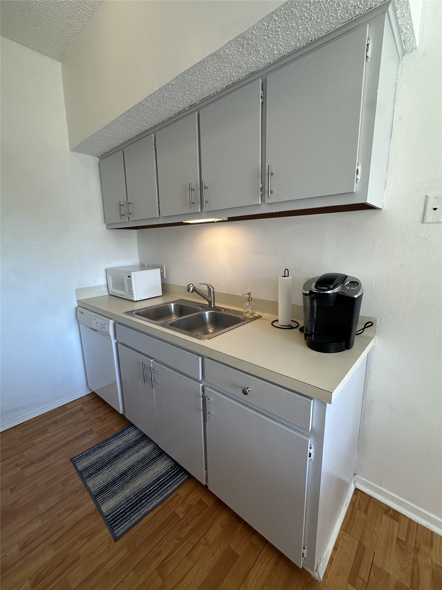 3316 Guadalupe Street, Unit 306 Austin, TX 78705 - Photo 26 of 28 Kitchen featuring gray cabinets, light wood-type flooring, light countertops, white appliances, and a textured ceiling