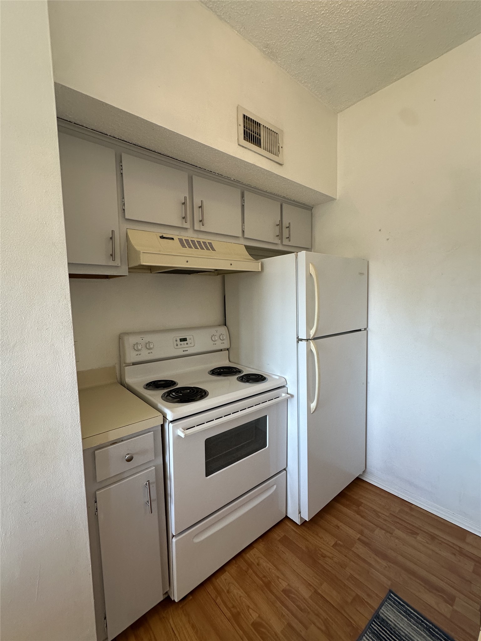 3316 Guadalupe Street, Unit 306 Austin, TX 78705 - Photo 27 of 28 Kitchen featuring white appliances, gray cabinetry, light wood-type flooring, light countertops, and under cabinet range hood