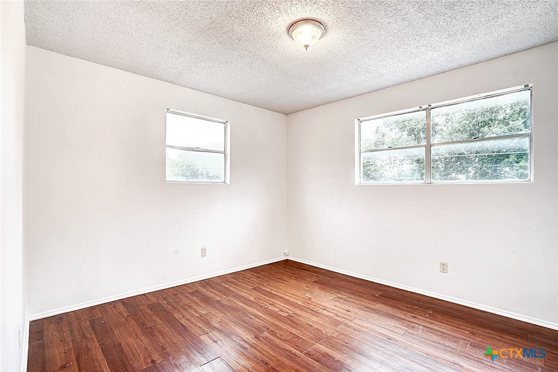 728 Old Martindale Road San Marcos, TX 78666 - Photo 14 of 16 an empty room with wooden floor and windows