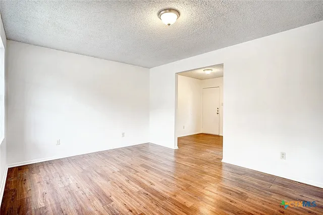 a view of an empty room with wooden floor and closet