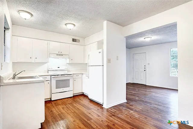 a kitchen with granite countertop white cabinets and white appliances