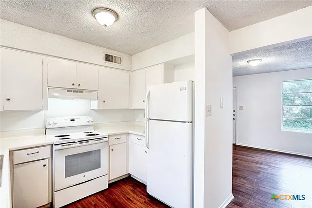 a kitchen with a refrigerator a stove top oven a sink and dishwasher with wooden floor