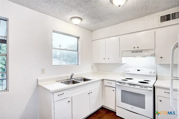 a kitchen with granite countertop white cabinets and white appliances