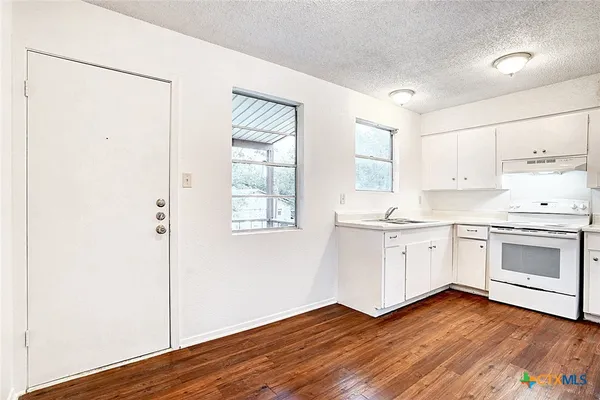 a kitchen with granite countertop white cabinets and white appliances