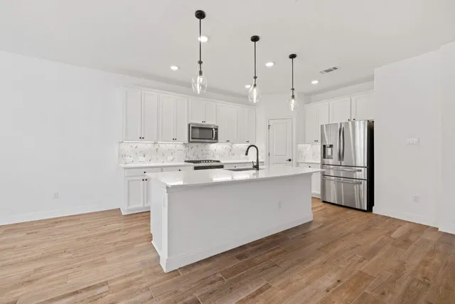 a kitchen with kitchen island white cabinets and stainless steel appliances