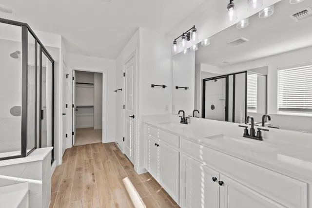 a spacious bathroom with a double vanity sink a mirror and a shower