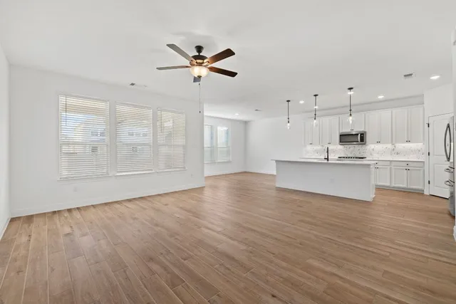 a view of an empty room with a window and wooden floor