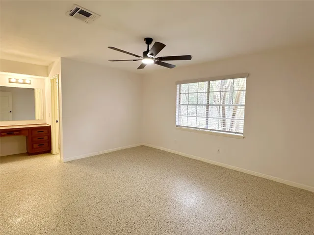 an empty room with windows and fan
