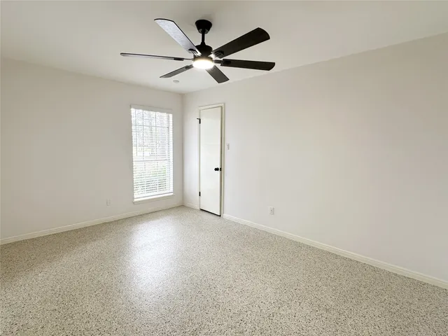 an empty room with windows and fan