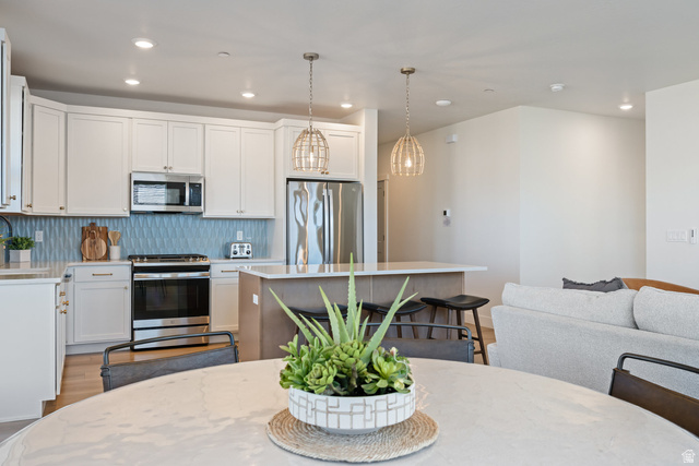 762 West Periwinkle Lane, Unit 102 St. George, UT 84790 - Photo 6 of 40 Kitchen with light wood-style floors, stainless steel appliances, a breakfast bar, a center island, and two tone color scheme