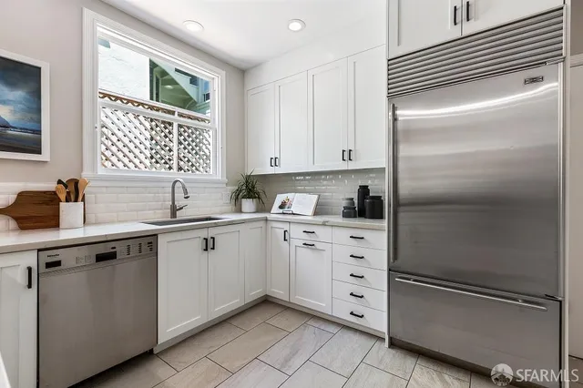a kitchen with white cabinets and a refrigerator
