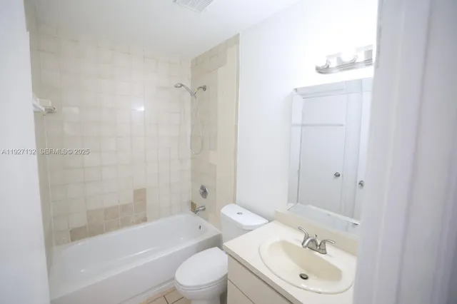 a bathroom with a bathtub shower sink vanity mirror and toilet