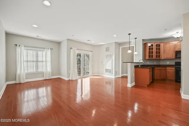 a view of an empty room with window and wooden floor