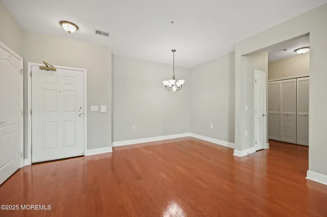 an empty room with wooden floor and mirror