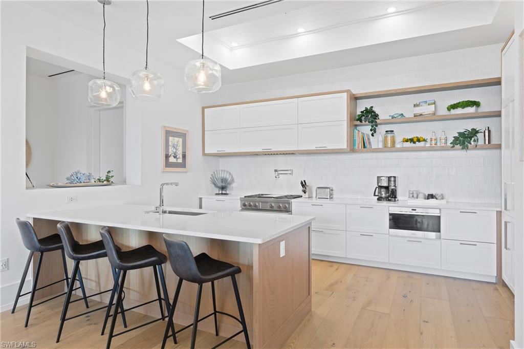 201 8th Street South, Unit 310 Naples, FL 34102 - Photo 3 of 40 a kitchen with a sink a stove a dining table and chairs