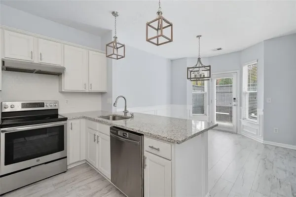 a kitchen with granite countertop stainless steel appliances a stove a sink and a refrigerator with wooden floor