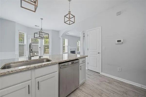 a kitchen with a sink dishwasher and white cabinets with wooden floor