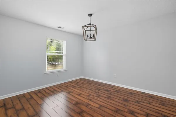 an empty room with wooden floor cabinet and windows