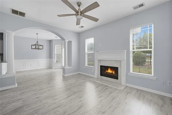 a view of an empty room with wooden floor fireplace and a window