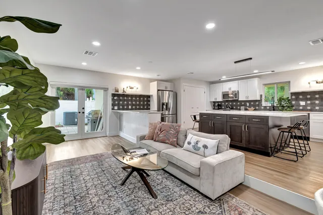 a living room with stainless steel appliances kitchen island granite countertop a couch and a coffee table