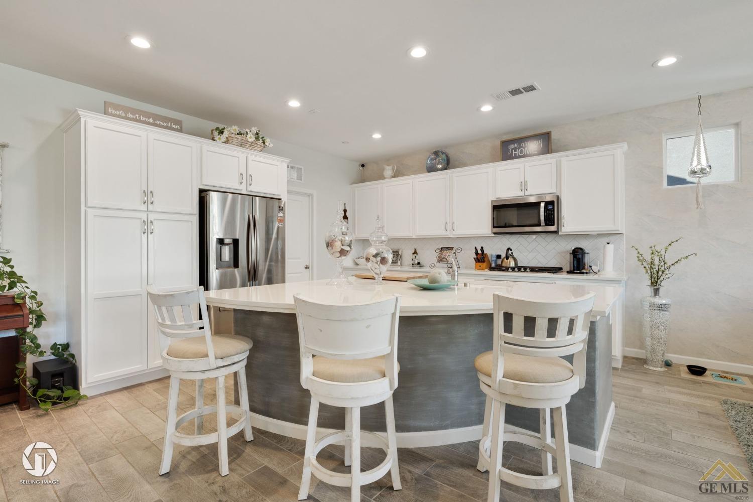 Undisclosed Address Bakersfield, CA 93311 - Photo 20 of 49 a kitchen with a dining table chairs refrigerator and microwave