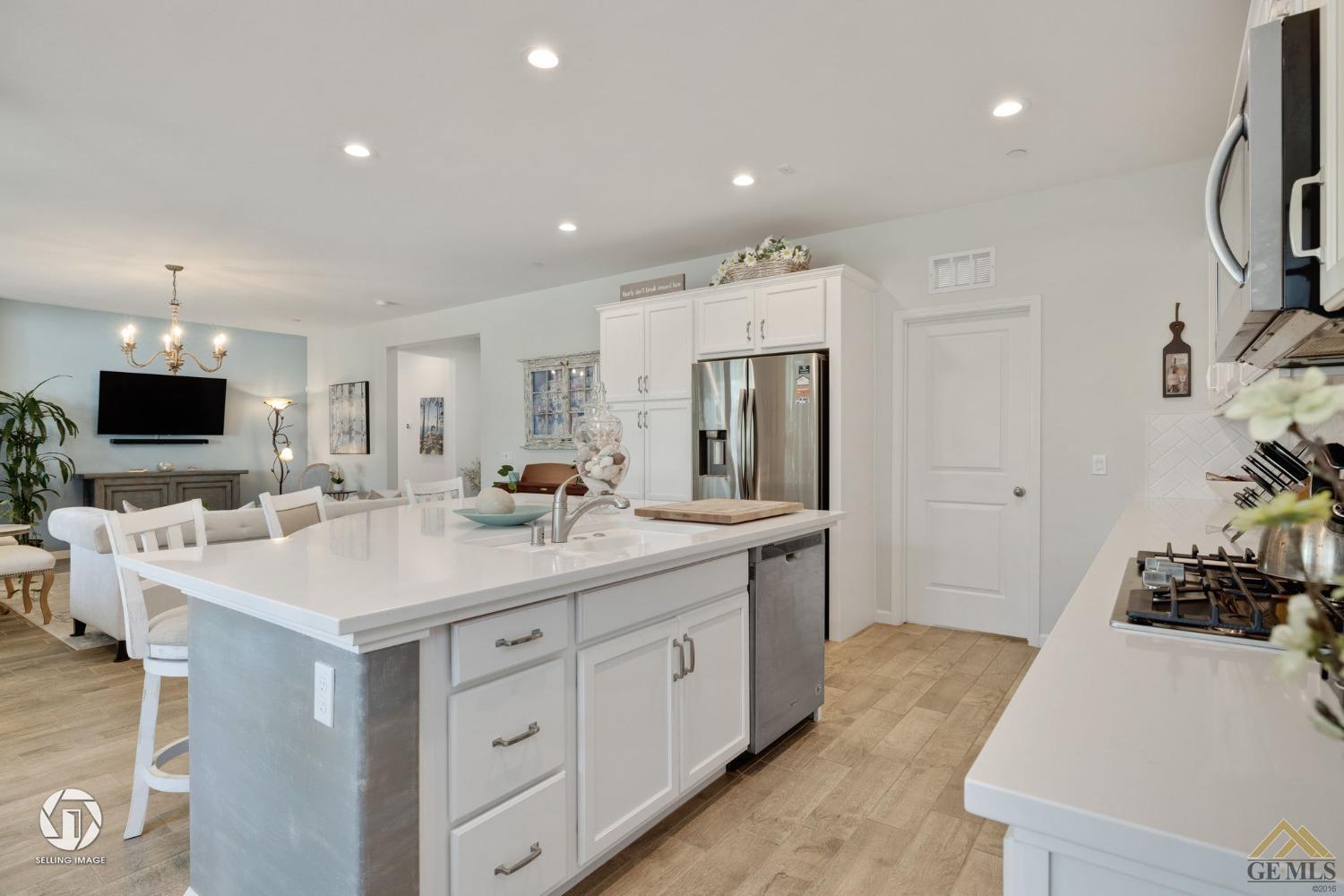 Undisclosed Address Bakersfield, CA 93311 - Photo 22 of 49 a large white kitchen with a sink and a large mirror with wooden floor