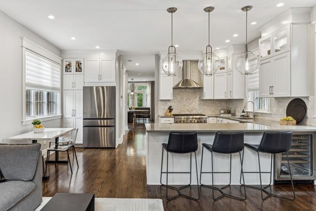 a kitchen with stainless steel appliances granite countertop a stove a refrigerator a kitchen island a dining table and chairs