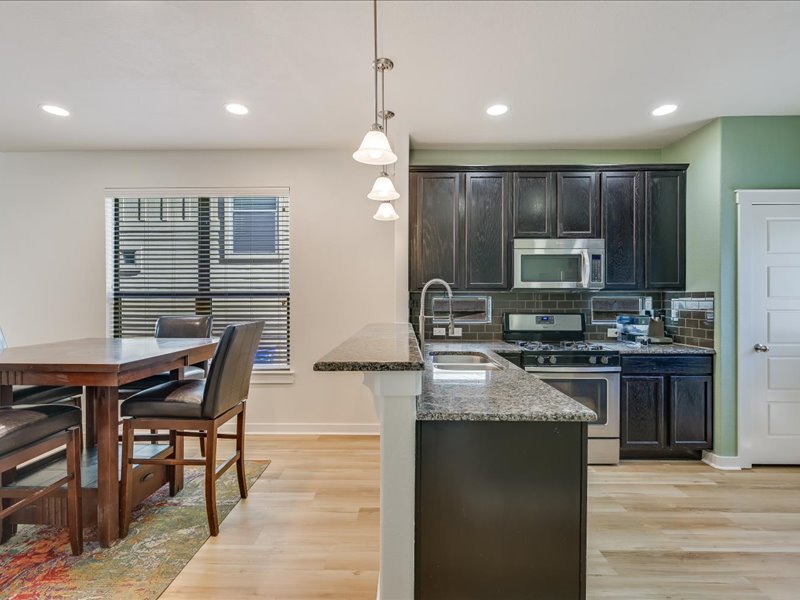 2101 Rivers Edge Way, Unit 29 Austin, TX 78741 - Photo 10 of 34 a kitchen with kitchen island granite countertop a stove top oven a sink dishwasher a dining table and chairs with wooden floor