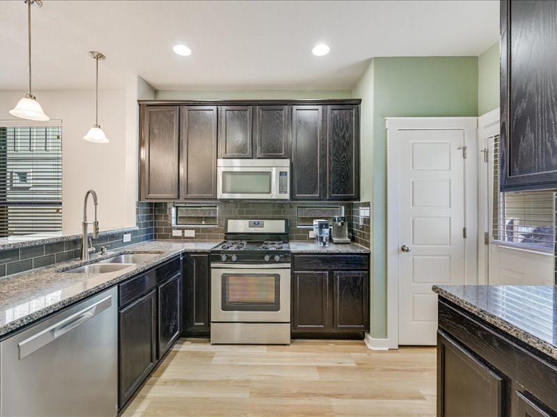 2101 Rivers Edge Way, Unit 29 Austin, TX 78741 - Photo 8 of 34 a kitchen with stainless steel appliances granite countertop a stove a sink and a refrigerator