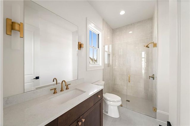 a bathroom with a granite countertop sink a toilet a shower and a mirror