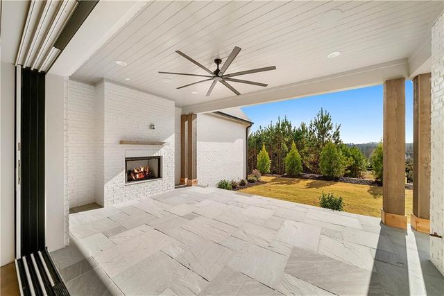 a view of a livingroom with a fireplace a ceiling fan and wooden floor