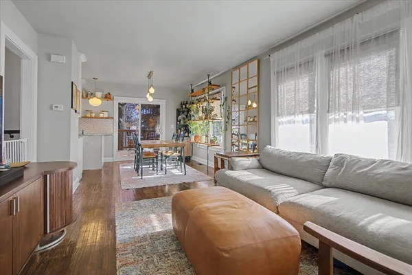 a dining room with wooden floor a chandelier a wooden table and chairs