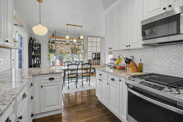 a kitchen with granite countertop a stove a sink and a refrigerator