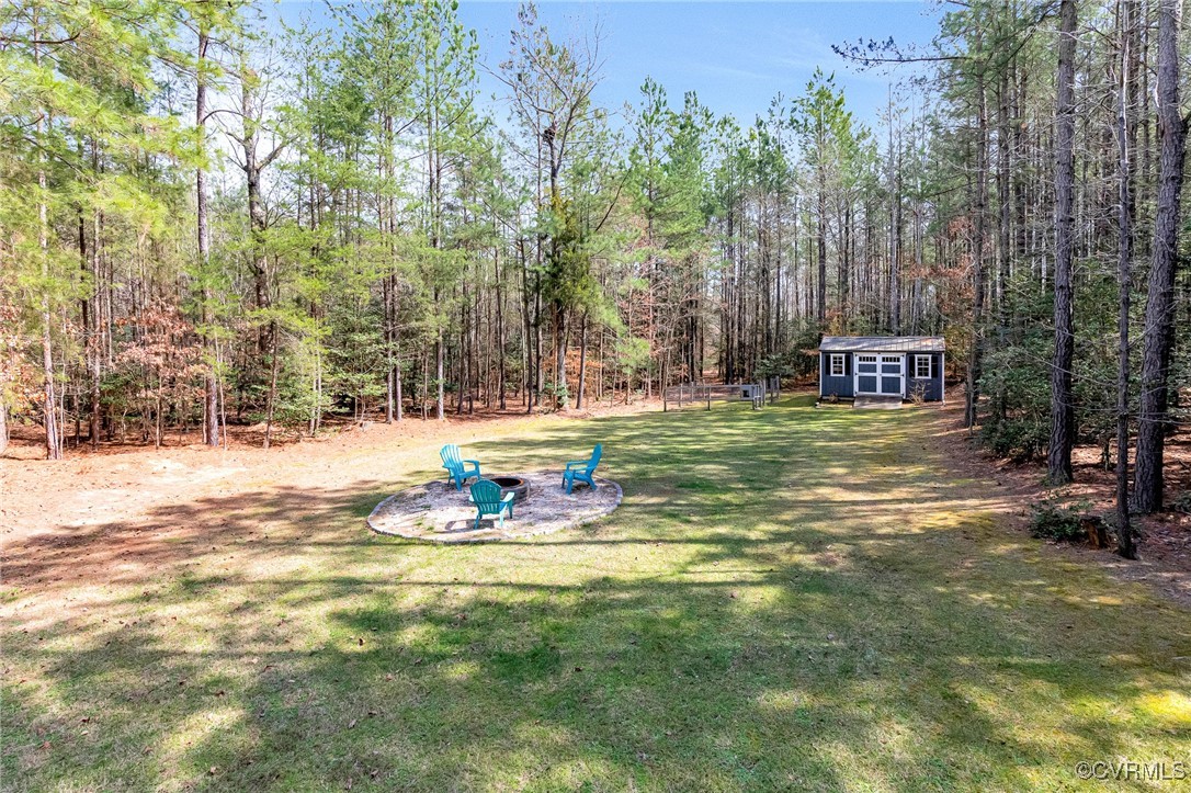 8773 Rock Cedar Road New Kent, VA 23124 - Photo 31 of 37 View of yard with a shed, a wooded view, and an ou